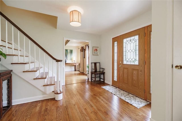 entryway featuring baseboards, stairs, and wood finished floors