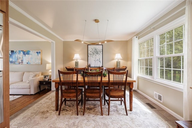 dining room featuring baseboards, visible vents, ornamental molding, and light wood-type flooring
