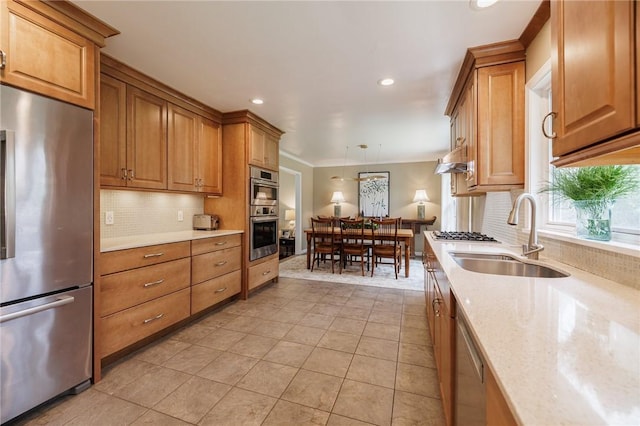 kitchen with a sink, backsplash, stainless steel appliances, and brown cabinetry