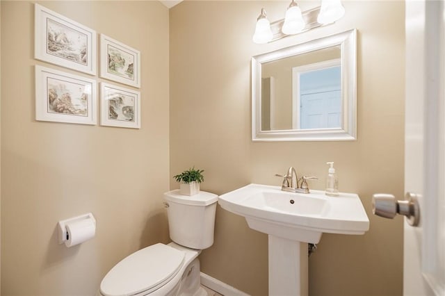 half bath with baseboards and toilet