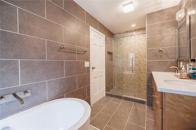 bathroom featuring tile walls, a freestanding bath, tile patterned floors, a sink, and a stall shower