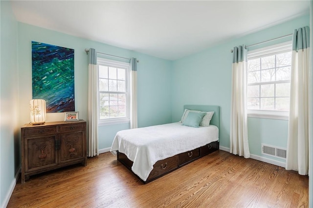 bedroom featuring baseboards, visible vents, and wood finished floors