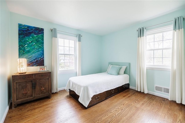 bedroom with visible vents, baseboards, and wood finished floors