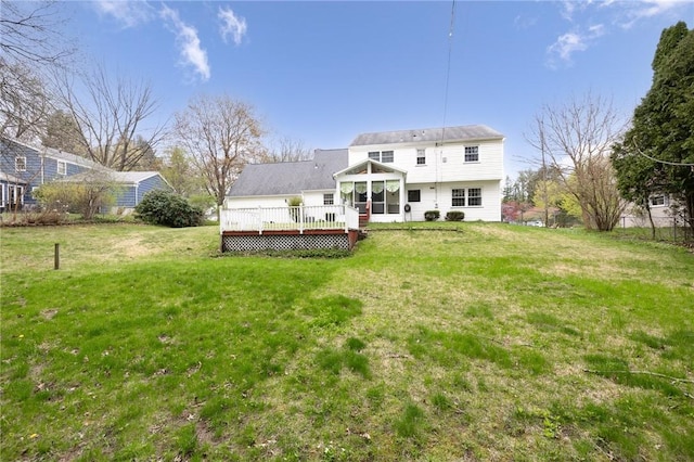 rear view of house featuring a sunroom, a wooden deck, and a yard