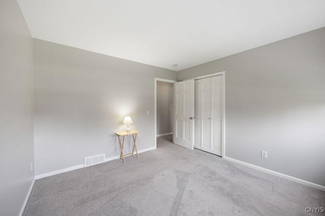 unfurnished bedroom with carpet floors, baseboards, visible vents, and a closet