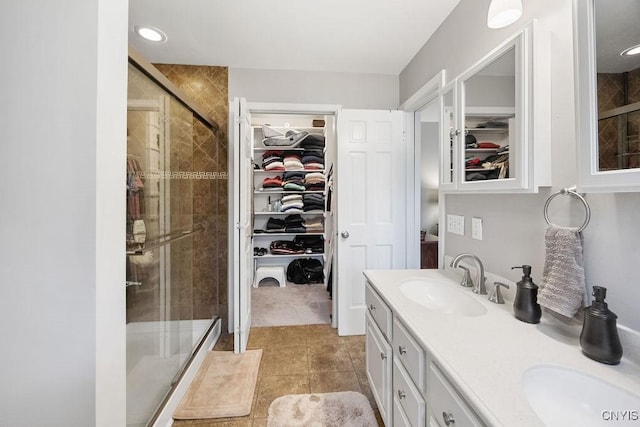 bathroom featuring double vanity, a sink, a walk in closet, and a shower stall