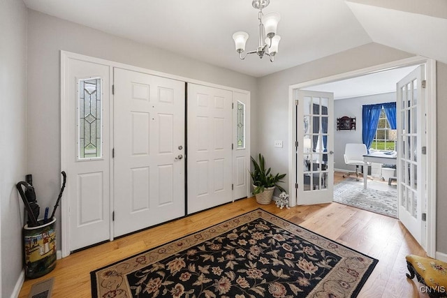 entryway with french doors, light wood finished floors, a chandelier, and visible vents