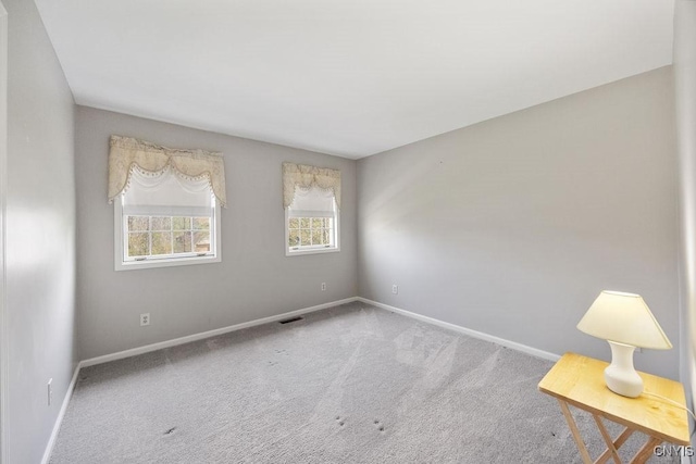 carpeted spare room featuring baseboards and visible vents