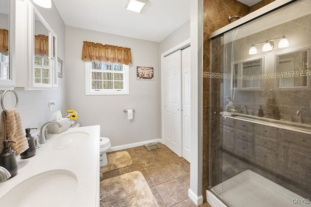 bathroom featuring a sink, a stall shower, toilet, and double vanity