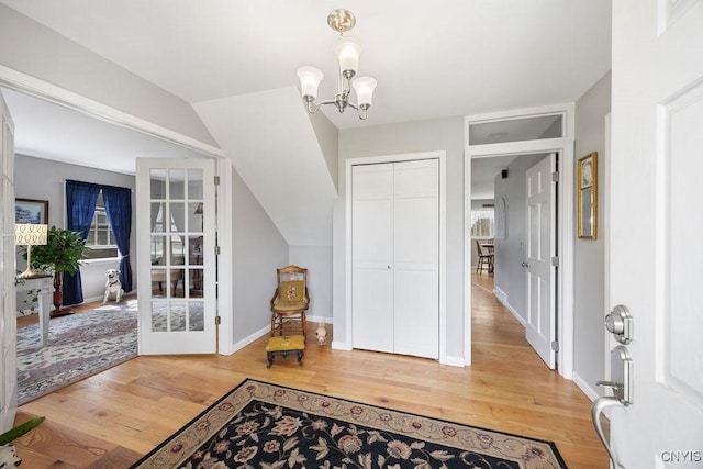 foyer entrance with baseboards, a notable chandelier, french doors, and light wood finished floors