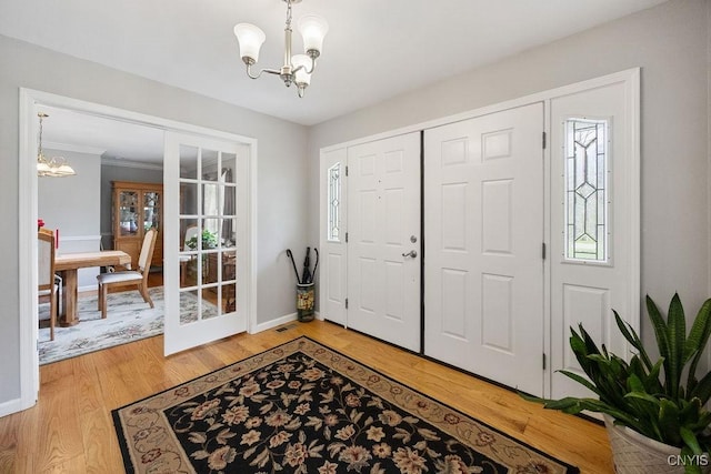 foyer featuring baseboards, a chandelier, french doors, and light wood-type flooring