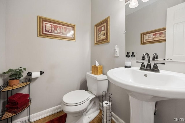 bathroom featuring baseboards, a sink, and toilet
