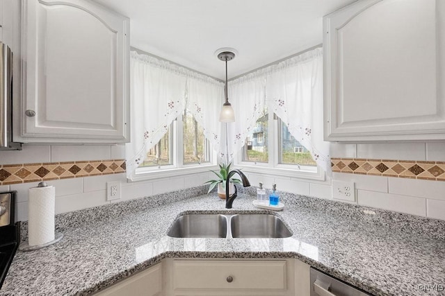 interior details with light stone counters, a sink, dishwasher, decorative backsplash, and pendant lighting