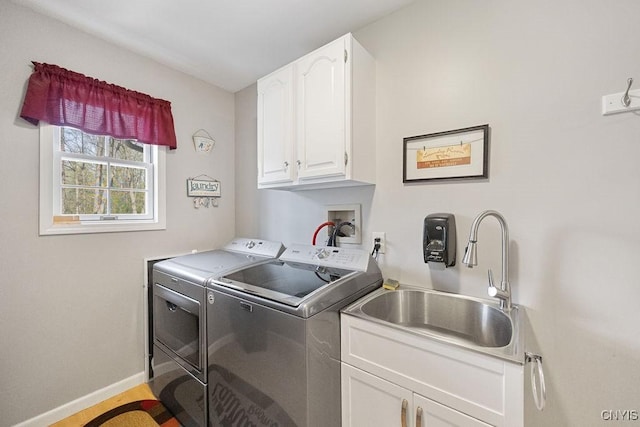 clothes washing area featuring baseboards, a sink, cabinet space, and washing machine and clothes dryer