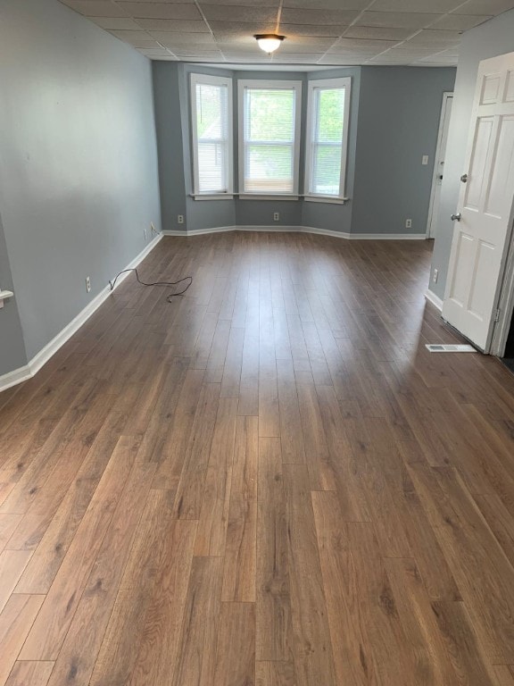 spare room with dark wood-style flooring, a wealth of natural light, and a paneled ceiling
