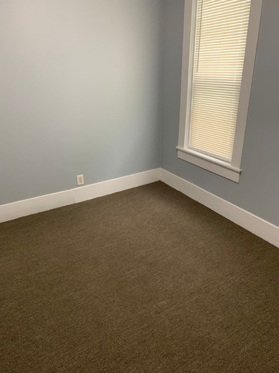 empty room featuring baseboards and dark carpet