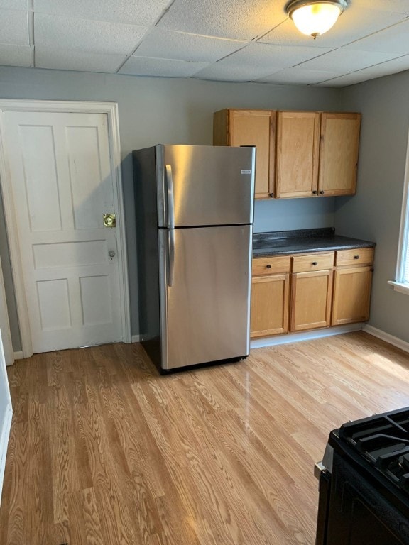 kitchen with freestanding refrigerator, dark countertops, light wood-style floors, a drop ceiling, and black range with gas cooktop