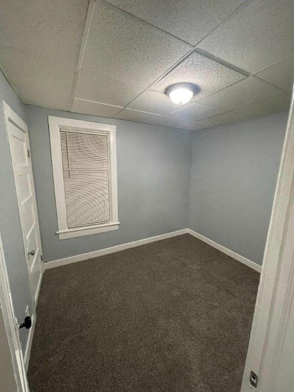 carpeted spare room featuring baseboards and a drop ceiling