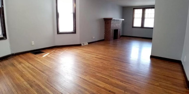 unfurnished living room with visible vents, wood finished floors, and a fireplace