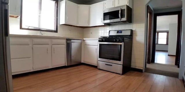 kitchen featuring light countertops, light wood-style flooring, appliances with stainless steel finishes, and white cabinetry