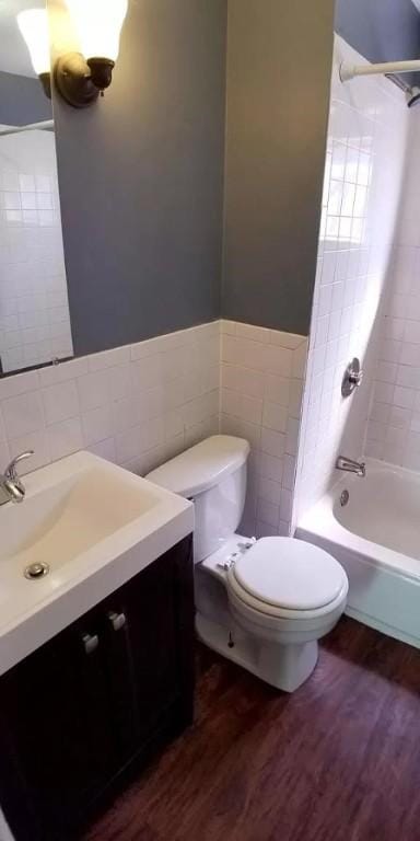 bathroom featuring tile walls, shower / bathing tub combination, toilet, and wood finished floors