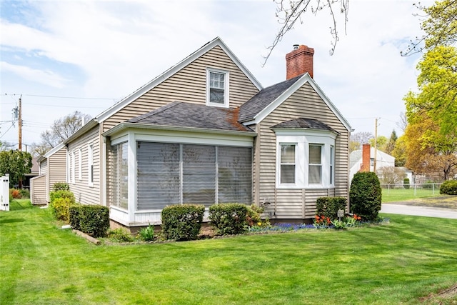 view of side of home featuring a lawn, a chimney, and a shingled roof