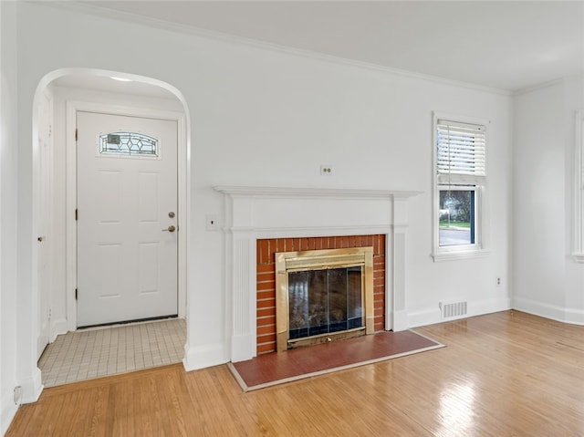 unfurnished living room with a wealth of natural light, ornamental molding, wood finished floors, and visible vents