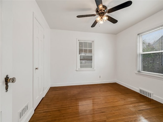 spare room with a ceiling fan, baseboards, visible vents, and wood finished floors