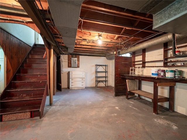 unfinished below grade area featuring electric panel and stairway