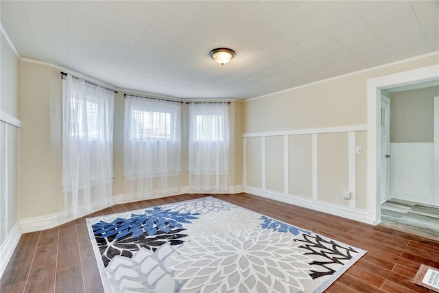 interior space with ornamental molding, wood finished floors, and visible vents
