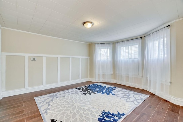 spare room featuring baseboards, ornamental molding, and wood finished floors