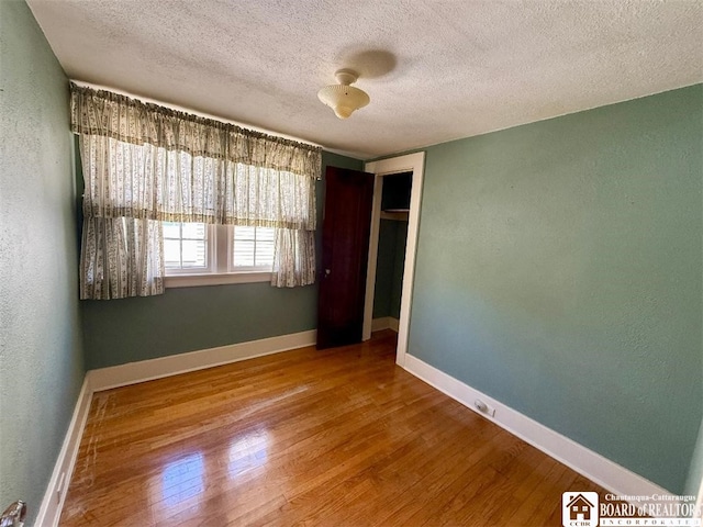148 Myrtle St, Jamestown, NY 14701 - unfurnished bedroom featuring a textured ceiling, a textured wall, a closet, and wood finished floors