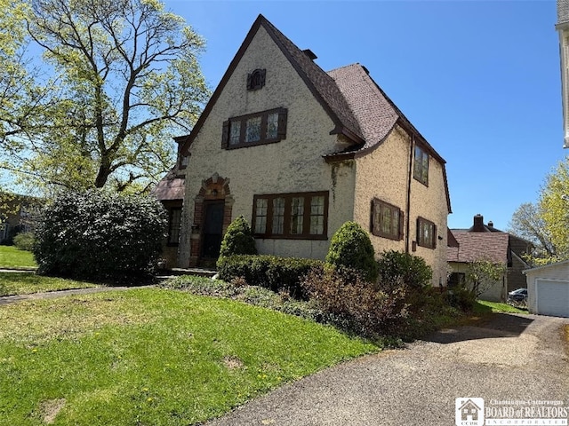 148 Myrtle St, Jamestown, NY 14701 - english style home with a garage, stucco siding, driveway, and a front lawn
