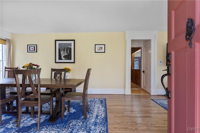dining area with baseboards and light wood finished floors