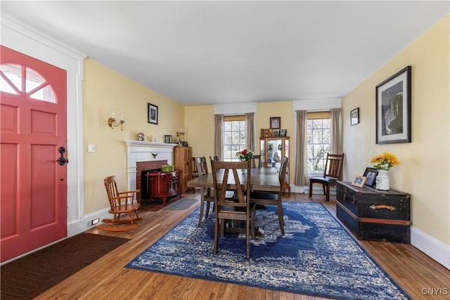 dining area featuring baseboards, wood finished floors, and a fireplace