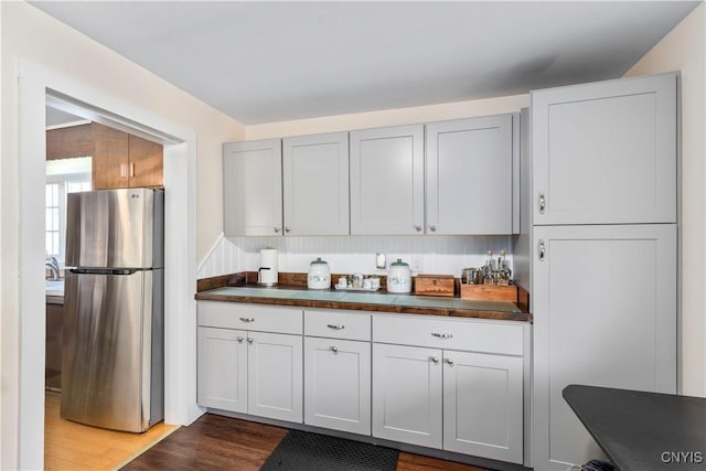 kitchen featuring freestanding refrigerator, wood finished floors, and dark countertops