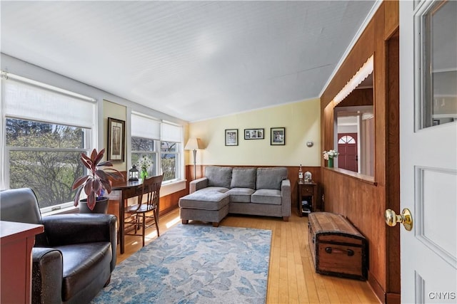 living area with light wood-style flooring, a wainscoted wall, and wooden walls
