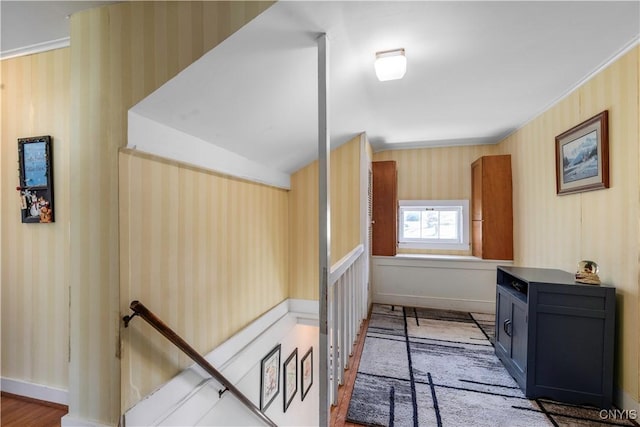interior space featuring baseboards, wallpapered walls, and wood finished floors