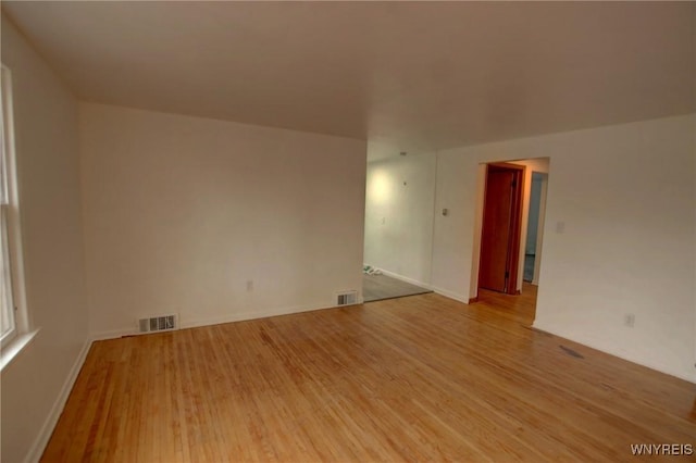 empty room featuring baseboards, visible vents, and light wood finished floors
