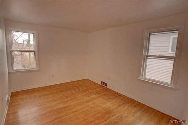 unfurnished room featuring baseboards, visible vents, and light wood-style floors