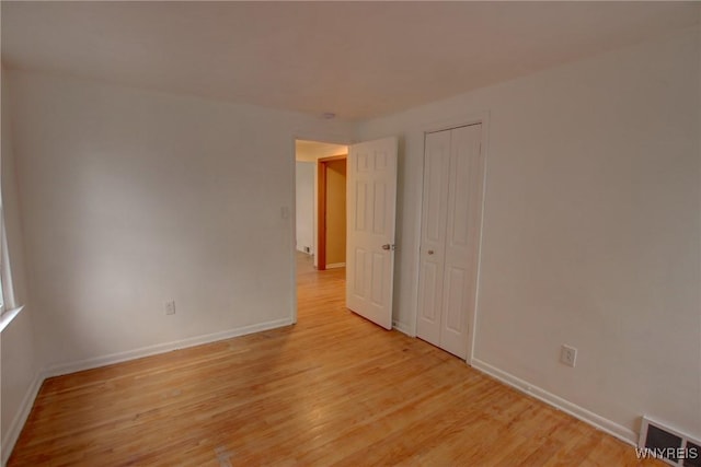 unfurnished room featuring baseboards, light wood-style flooring, and visible vents