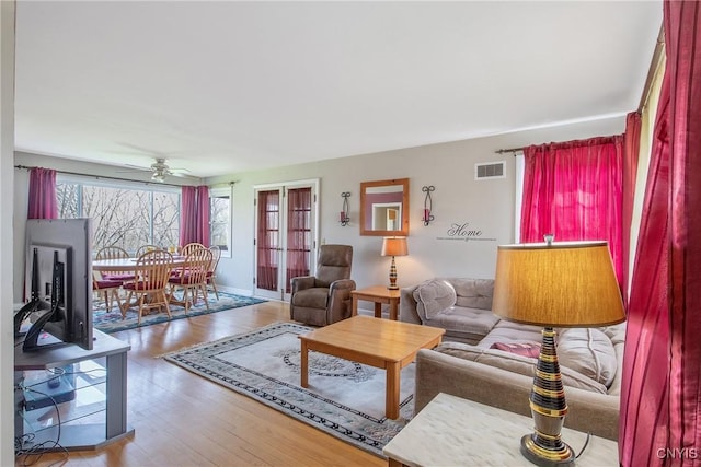 living area with ceiling fan, visible vents, and wood finished floors