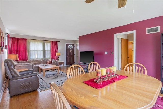 dining space with visible vents, a ceiling fan, and hardwood / wood-style flooring