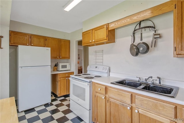 kitchen with a sink, tile patterned floors, white appliances, and light countertops