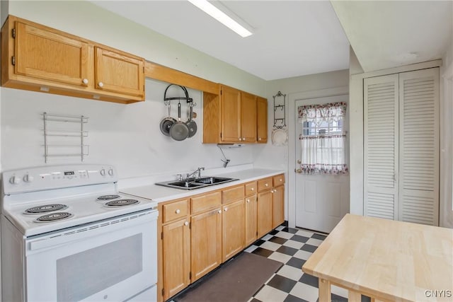 kitchen with a sink, dark floors, white range with electric cooktop, and light countertops