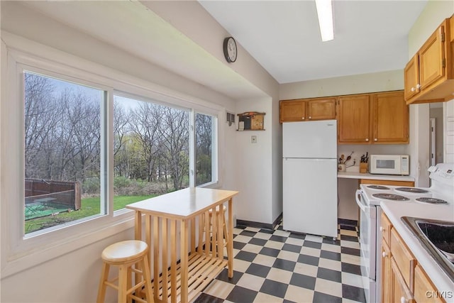 kitchen with light countertops, light floors, a wealth of natural light, and white appliances