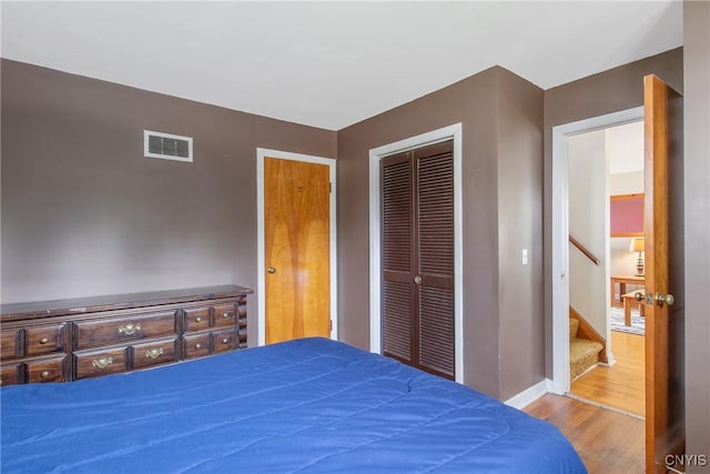 bedroom featuring visible vents, baseboards, wood finished floors, and a closet