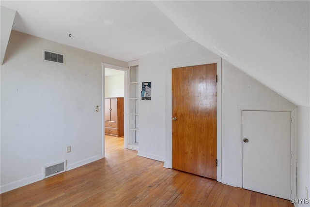 additional living space featuring lofted ceiling, hardwood / wood-style flooring, and visible vents