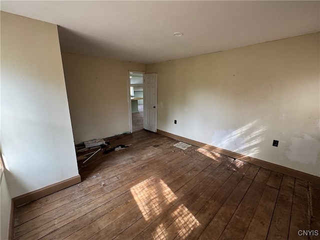 spare room featuring baseboards and hardwood / wood-style flooring
