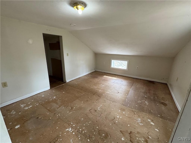 additional living space with baseboards and vaulted ceiling